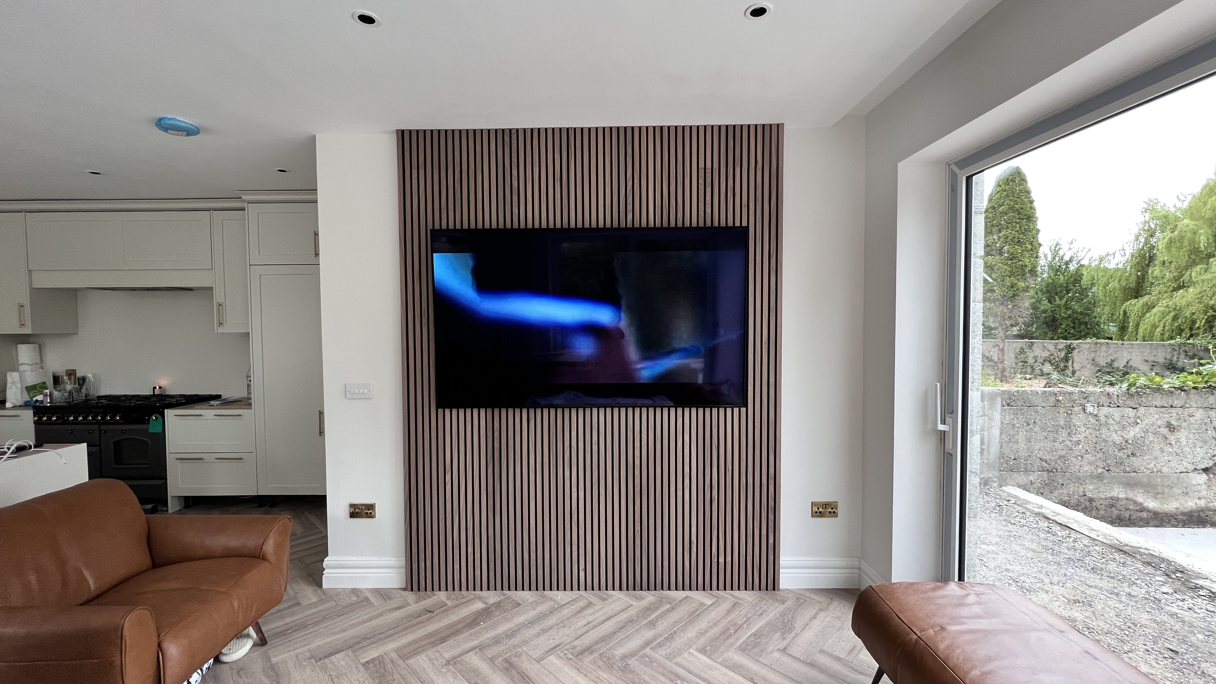 A professional TV installer carefully mounting a flat-screen television onto a living room wall, ensuring optimal viewing angles
